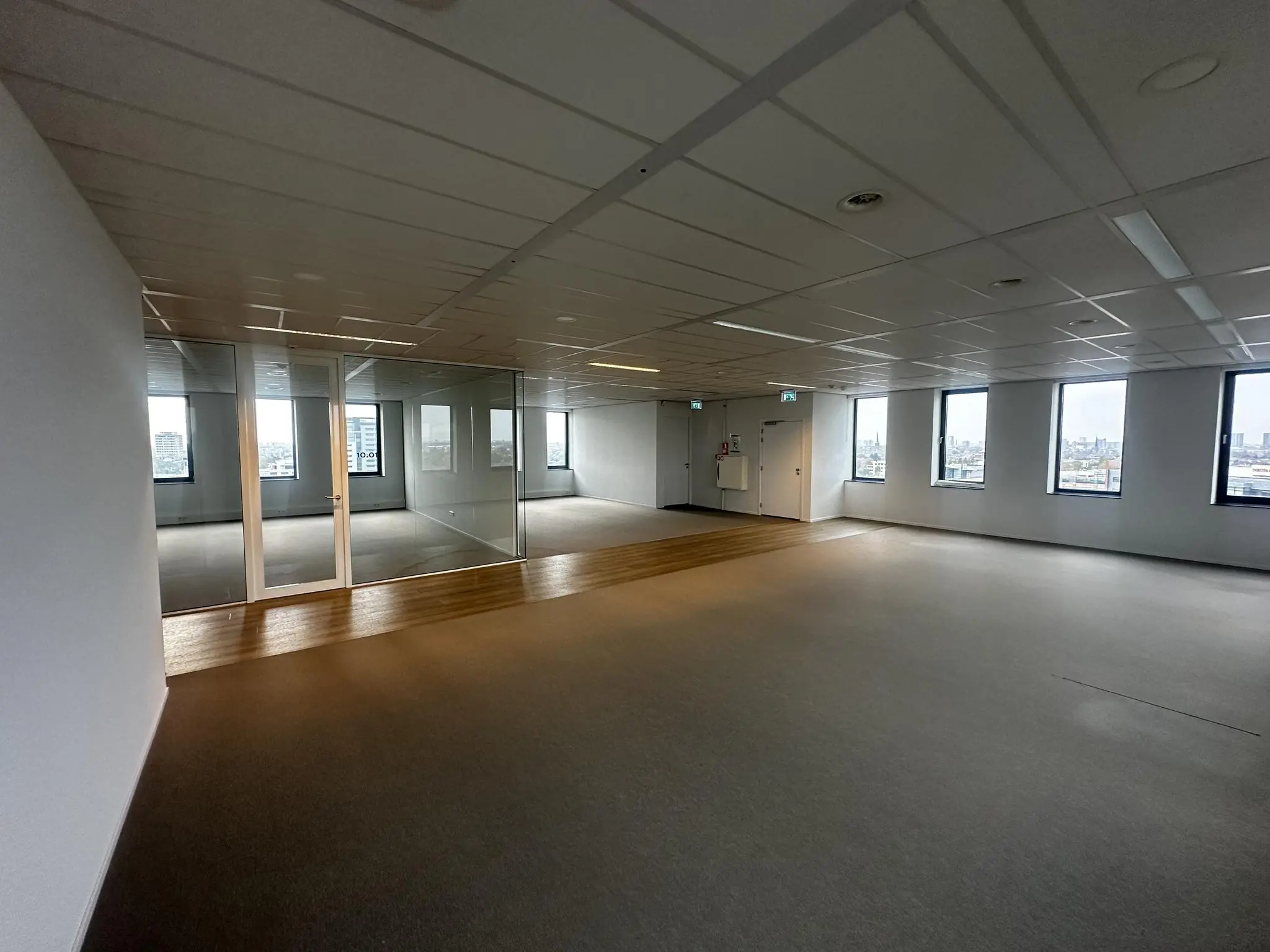 Leeg kantoorpand aan de Laan van Zuid Hoorn met grote ramen, glazen tussenwand en uitzicht op de stad.
